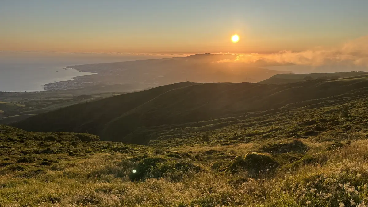 O sol a pôr-se sobre a costa norte de São Miguel, visto das pastagens altas
