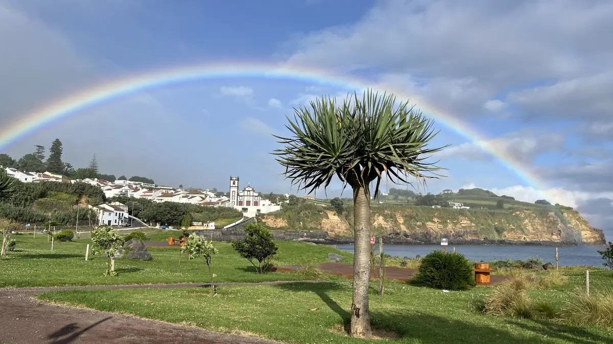 Um arco-íris sobre uma aldeia açoriana caiada de branco à beira-mar