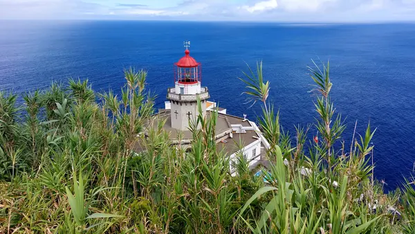 Um farol vermelho e branco nas falésias sobre o Atlântico azul-escuro